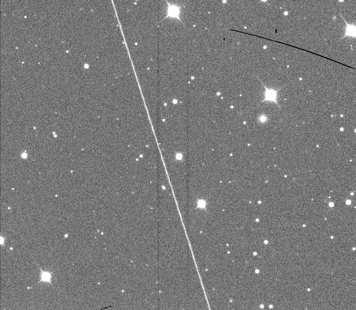 A grayscale image of stars disrupted by a satellite streak.