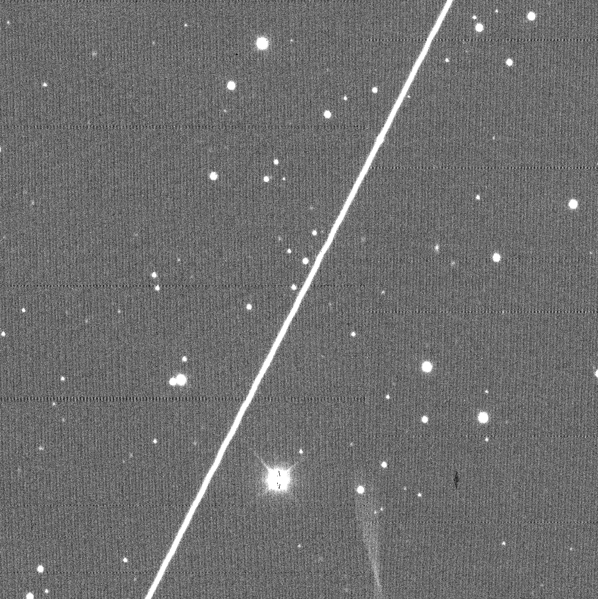 A grayscale image of stars disrupted by a satellite streak.